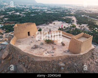 Couple at Dhayah Fort rock fortress in Ras al Khaimah emirate of the United Arab Emirates aerial view at sunset Stock Photo