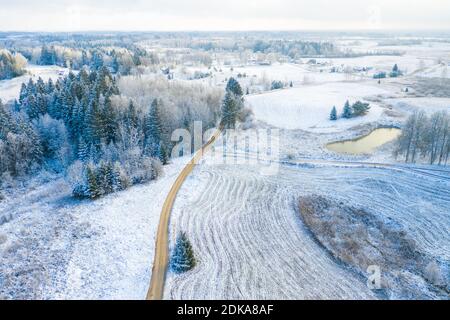 Windy winter road in snow covered forest, top down aerial view. Stock Photo