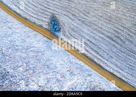 Windy winter road in snow covered fields, top down aerial view. Stock Photo