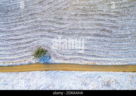 Windy winter road in snow covered forest, top down aerial view. Stock Photo