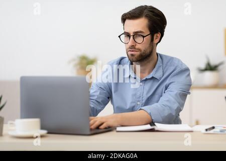 Businessman Frowning Working On Laptop Having Difficult Task At Workplace Stock Photo