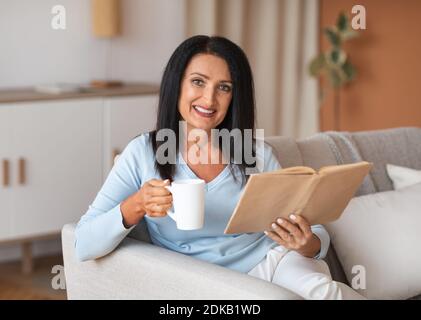 Mature lady holding cup of coffee and book Stock Photo