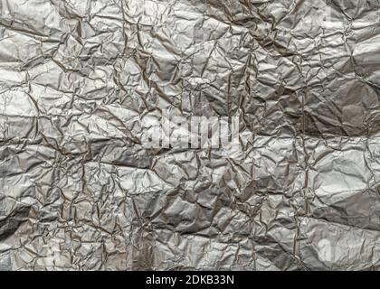 Wrinkled metal foil texture, silver color abstract background. Stock Photo
