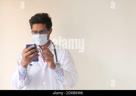 young doctor in face mask using smart phone indoor  Stock Photo