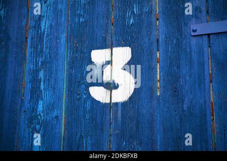 Number three on an old abandoned weathered blue bright colour wooden gate in Budapest suburb, Hungary Stock Photo