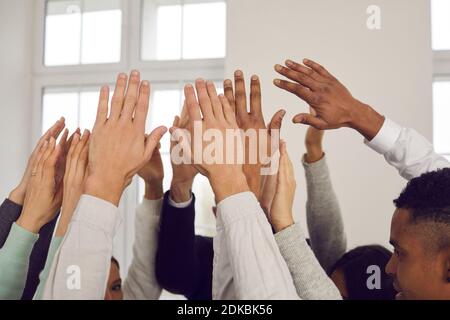 Team of multiracial people raising hands up in the air, showing solidarity, unity and support Stock Photo
