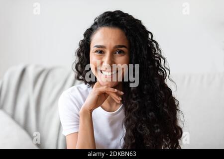 Closeup portrait of dark-haired curly woman posing at home Stock Photo