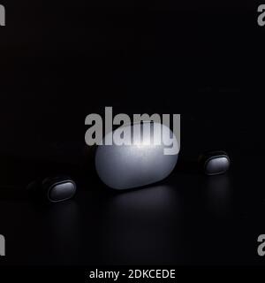 Black bluetooth headphones with charging caase on black background. Stock Photo