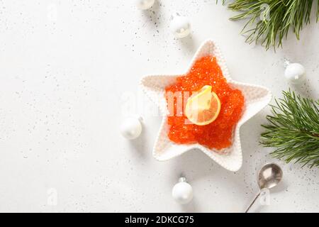 Bowl in shape of star with red caviar served for Christmas festive dinner on white table. View from above. Space for text. Stock Photo