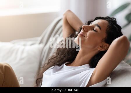 Relaxed young woman resting at home, side view Stock Photo