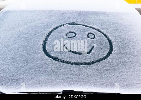 image of a smiling face in the snow on the windshield of a car on a frosty winter day Stock Photo