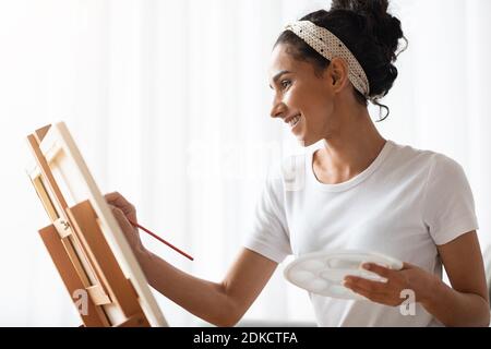 Young woman artist painting at home, side view Stock Photo