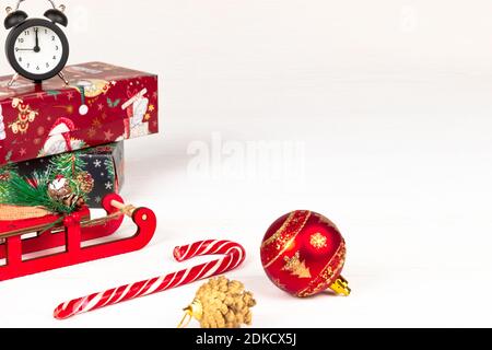 santa claus sleigh, alarm clock, santa claus staff, golden christmas tree cone and boxes with gifts on a white wood background with gold veins Stock Photo