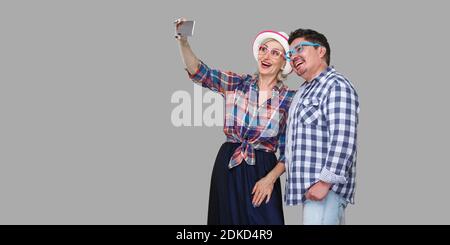 Couple of friends, cute adult man and woman in casual checkered shirt standing together and making selfie foto for memory or video call, toothy smile. Stock Photo
