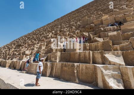 Lots of tourists climbing the Pyramid of Khufu in The Giza pyramid complex, an archaeological site on the Giza Plateau, on the outskirts of Cairo, Egy Stock Photo