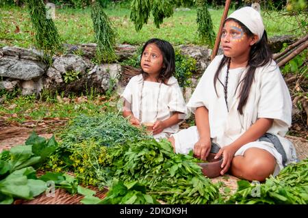 Happy Indian children in Mayan village. Young girls sitting on mats during a Mayan ceremony, Mexico Stock Photo