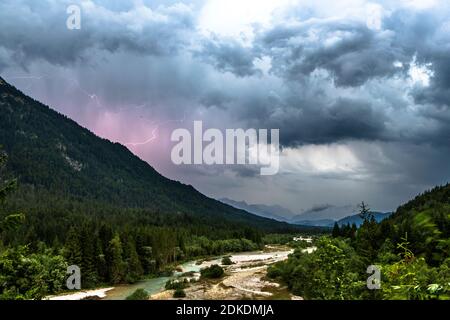 Thunderstorm over the Isar near Wallgau, lightning discharge and dark clouds, in the background partly a slight view of the Zugspitze and the Wettertsiengebirge. Stock Photo