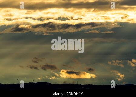 Evening light and cloud mood over three wind turbines in the foothills of the Alps near Weilheim. Stock Photo