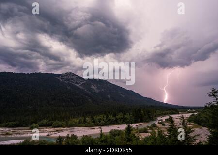 Thunderstorm over the Isar near Wallgau, lightning discharge and dark clouds, in the background partly a slight view of the Zugspitze and the Wettertsiengebirge. Stock Photo