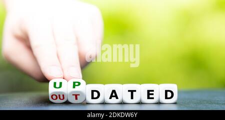 Hand turns dice and changes the word outdated to updated. Stock Photo