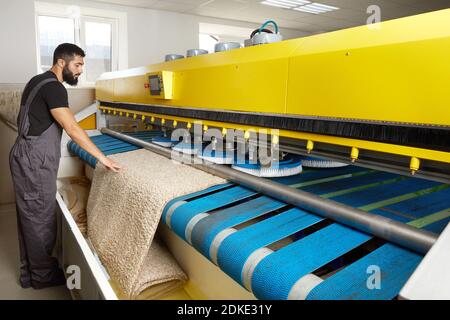 Man operating carpet automatic washing machine in professional laundry service Stock Photo