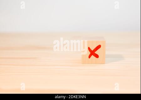 Concept of negative decision making or choice of rejection. cross mark x on wooden cube. red cross sign on the edge of a wooden cube. Stock Photo