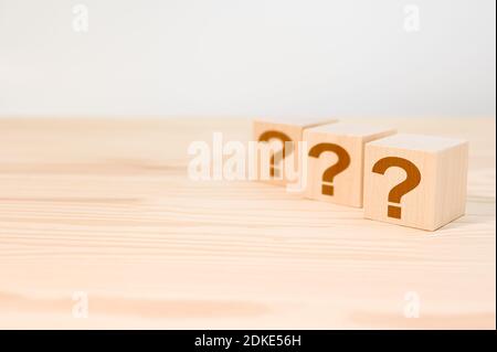Cubes with question marks on wooden background, closeup. Wooden cube block shape with sign question mark symbol on wood table. Copy Space Stock Photo