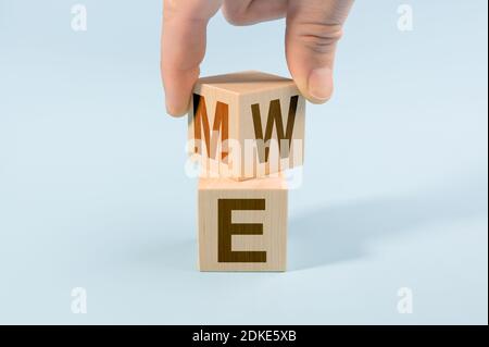 Hand flip wood cube with me or we on blue background. Teamwork concept. Hand turns dice and changes the word ME to WE. copy space Stock Photo