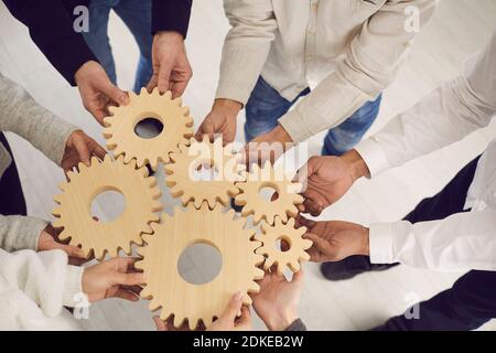 Close up of hands of office workers connecting together gears to each other on the desk. Stock Photo