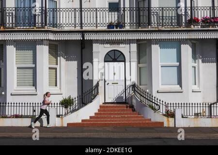 England, East Sussex, Eastbourne, Woman Running Past Seafront Building Stock Photo