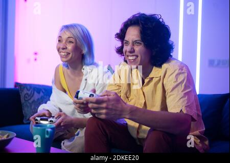 Happy boyfriend and girlfriend playing video games and holding