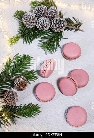 Fig macarons beautifully arranged on a white table, winterly decorated with fir branches and pine cones, a LIchter chain glows in the background Stock Photo