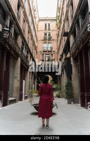 Young brunette girl in red dress stands near old houses in Barcelona Stock Photo