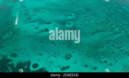 Tourist motor boat on the surface of turquoise water in tropical lagoon, aerial view. Seascape with beach on tropical island. Summer and travel vacation concept. Boracay Island, Philippines Stock Photo