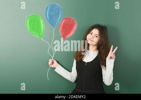 Portrait of pre-adolescent child is holding a bunch of  painted balloons. High resolution photo. Full depth of field. Stock Photo