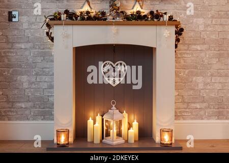 Homely Christmas mantle piece with candles and pine cone garland Stock Photo