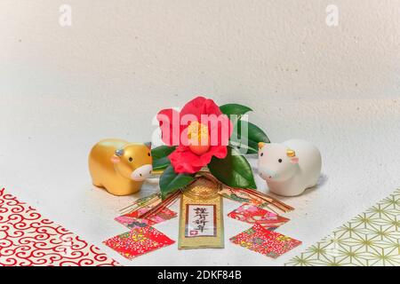 Japanese New Year's Card with handwriting ideograms Kingashinnen or Happy New Year on a traditional decoration with a Tsubaki flower and two Zodiacal Stock Photo