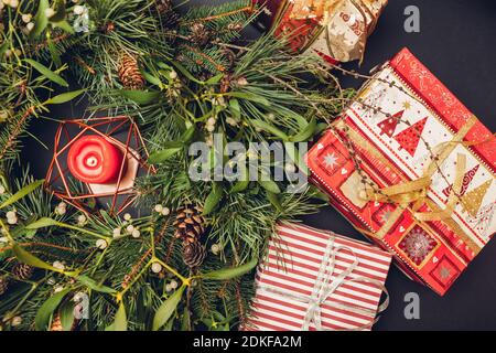 Christmas and New Year wreath made of fir, pine, mistletoe branches, cones with burning candle inside and gift boxes. Eco and natural home decoration Stock Photo