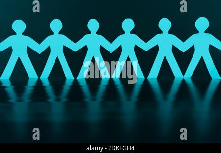 Paper men as a human chain against a black background Stock Photo