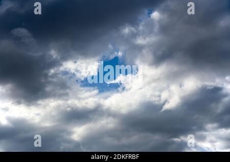 Eye of the clear blue sky, opened in the depths of the cloudy sky before the storm. The symbol of purity and hope. Stock Photo