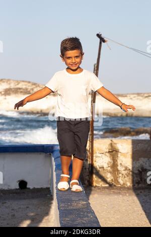 Cute boy doing balance on a wall in summer