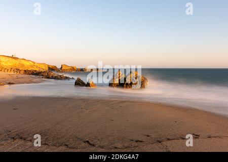 Stunning long-exposure view of smooth waves crashing into rock formations at sunset, Sequit Point, Leo Carrillo State Beach, Malibu, California Stock Photo