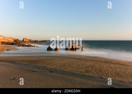 Stunning long-exposure view of smooth waves crashing into rock formations at sunset, Sequit Point, Leo Carrillo State Beach, Malibu, California Stock Photo