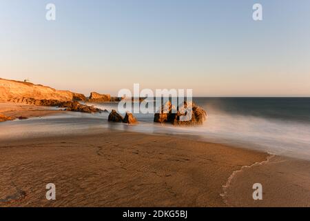 Stunning long-exposure view of smooth waves crashing into rock formations at sunset, Sequit Point, Leo Carrillo State Beach, Malibu, California Stock Photo