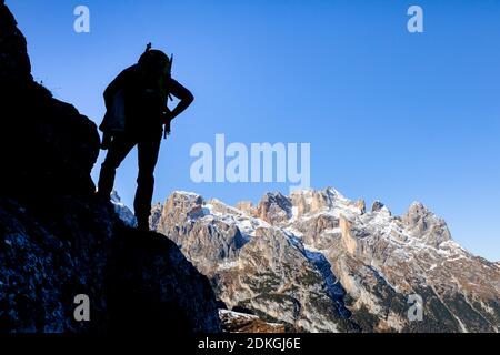 Italy, Veneto, Belluno province, Taibon Agordino. Mountaineer in silhouette in front of the pale di san martino (northern chain), Dolomites Stock Photo