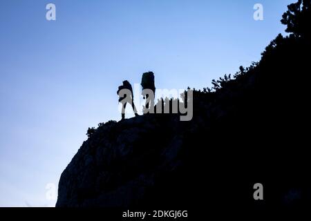 Italy, Veneto, Belluno province, Taibon Agordino. Two mountaineers in silhouette in a wild alpine environment, Dolomites Stock Photo