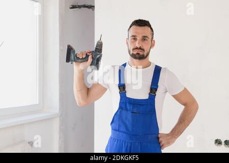 A repairman holds a drill in his hand and looks at the camera Stock Photo
