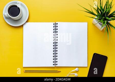 Notebook mockup on yellow office desk. Top view. Isolated blank sheet for design, list, script, text, draw, annotations and creativity. Pencil, cup of Stock Photo