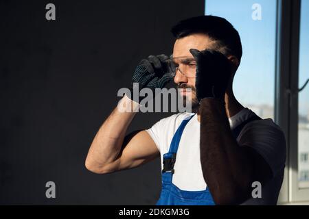 The worker is in a dark room. He puts on safety glasses Stock Photo