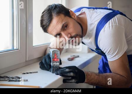 The worker measures the distance from the window with a level Stock Photo